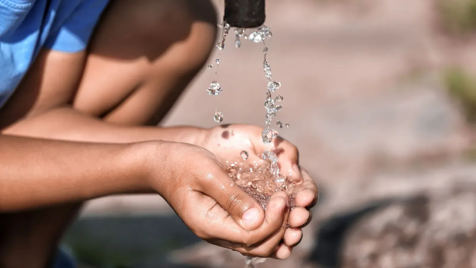 Child's cupped hands holding clean water at a South African school