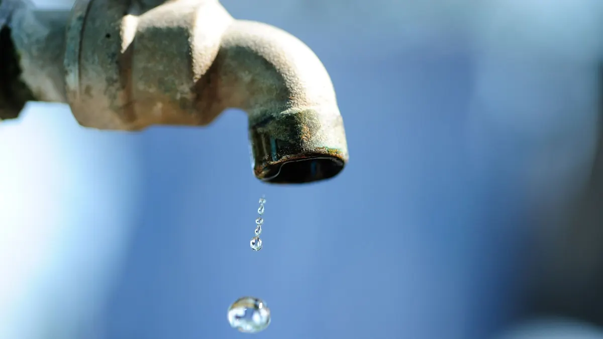 Rusted tap dripping against a blue sky, symbolising Johannesburg's failing municipal supply